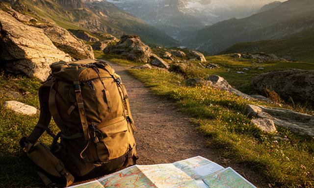 Wanderweg in den Schweizer Alpen mit Karte und Rucksack im Vordergrund